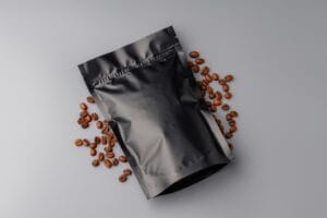A bag of premium coffee beans surrounded by scattered coffee beans on a gray background