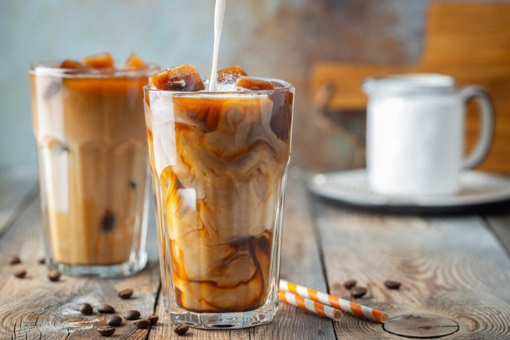 ice-coffee-in-a-tall-glass-with-cream-poured-over-coffee-ice-cubes-and-beans--1024x682 Café Tem Calorias? A Verdade Definitiva Sobre o Cafezinho e a Balança