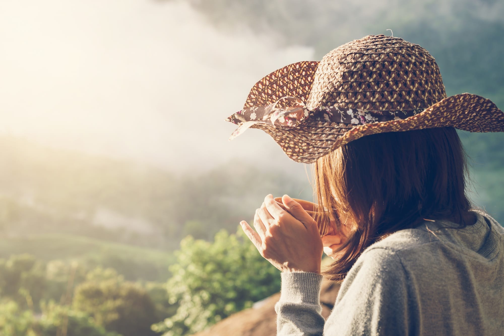 Woman holding a cup of coffee with beautiful landscape